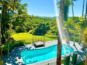 una piscina con altalena e palme di Jackaroo Treehouse Rainforest Retreat a Mission Beach