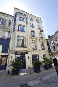 a tall building with potted plants in front of it at Hôtel La Tour Intendance in Bordeaux