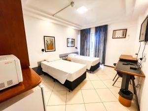 a hotel room with two beds and a desk at Apart Hotel em Brasília - MA Empreendimentos in Brasília