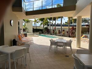 un patio con mesas y sillas y una piscina en Exclusive Apartment with Ocean Views en Caloundra