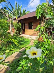 a wooden house with a garden and flowers at Happy Farm Tien Giang Homestay in My Tho
