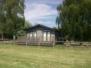 a tiny house with a porch and a fence at Lodge in beautiful Kent countryside with fine views in Brookland