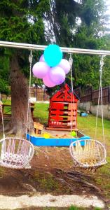 une balançoire dans un parc avec une maison et un ballon dans l'établissement Tsemi My House, à Bordjomi