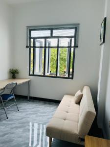 a living room with a couch and a desk and a window at Koi Guest House - Phan Thiết in Ấp Thiện Phước