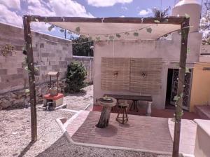 een achtertuin met een tafel en een boomstronk bij Qué Chula casa. in Izamal