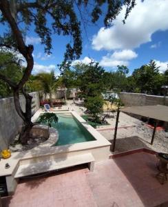 a swimming pool with a table and a tree at Qué Chula casa. in Izamal