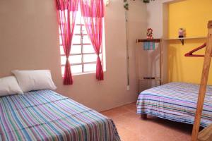 1 dormitorio con 2 camas y ventana en Qué Chula casa., en Izamal
