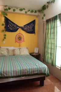 een slaapkamer met een bed in een kamer met een raam bij Qué Chula casa. in Izamal