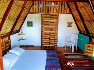 a bedroom with a bed in a room with wooden walls at Playa Kai Glamping in La Punta de los Remedios