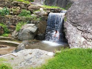 a person is standing in a waterfall at Hill Ventures - Swiss Glamping with Adventure Activities in Dharamshala