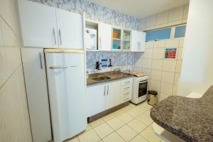 a kitchen with white cabinets and a refrigerator at Thermas Paradise - Rio Quente - Apto 2 quartos com Suíte in Rio Quente