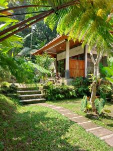 a house with a palm tree in front of it at Pondok Kukuh villa Sidemen in Sidemen