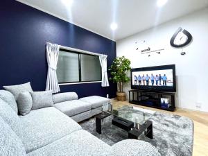 guesthouse Nakatsu في أوساكا: غرفة معيشة مع أريكة وتلفزيون