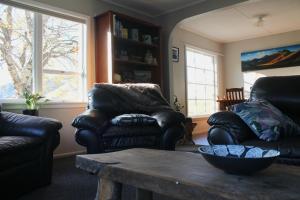 Sala de estar con 2 sillas de cuero y mesa de centro en Bauchops Hill Station Farmstay en Burkes Pass