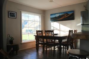 una sala da pranzo con tavolo, sedie e finestra di Bauchops Hill Station Farmstay a Burkes Pass