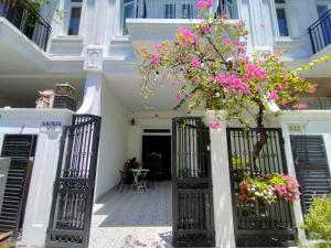 a white house with black gates and pink flowers at Aroma home in Da Nang