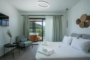 a bedroom with a large white bed and a chair at Nόka Suite Apartments in Faliraki