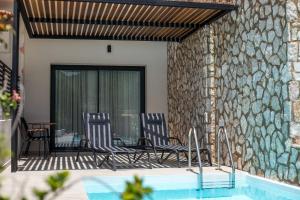 um pátio com 2 cadeiras e uma piscina em Nόka Suite Apartments em Faliraki