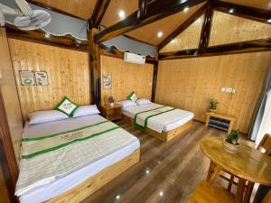 twee bedden in een kamer met houten wanden en houten vloeren bij Homestay Lê Gia in Xuyên Mộc
