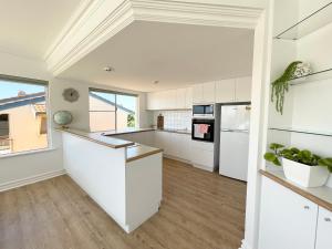 a kitchen with white cabinets and a large window at Sailors View Kalbarri in Kalbarri +9 photos