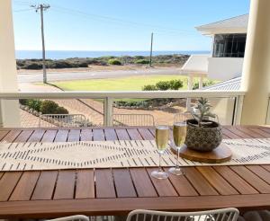 a wooden table with two wine glasses on a balcony at Sailors View Kalbarri in Kalbarri