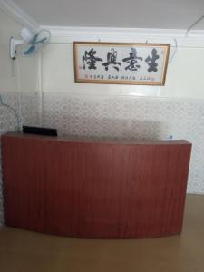 a wooden reception desk with a sign on the wall at 华越宾馆 in Phnom Penh
