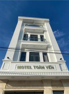 ein weißes Gebäude mit einem Schild an der Seite in der Unterkunft Khách Sạn Toàn Yến - Nhơn Lý in Hưng Lương