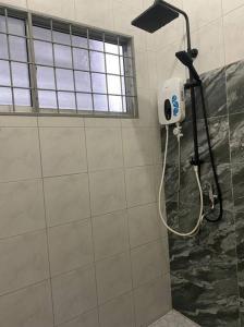 a shower in a bathroom with a blow dryer on a wall at Lisa Homestay Sandakan in Sandakan