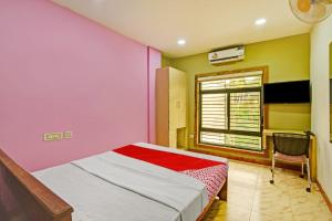 um quarto com paredes cor-de-rosa e amarela e uma cama em OYO Flagship Karipur Residency em Kondotti