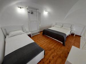 2 Betten in einem Zimmer mit Holzböden und weißen Wänden in der Unterkunft Casa vacanze Mezzanine in Catania