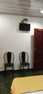 two chairs in a room with a table and a door at Floral Homestay in Thekkady