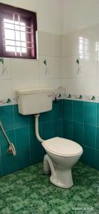 a bathroom with a white toilet and a window at Floral Homestay in Thekkady