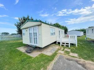 a tiny house with a bench in a yard at Caravan At Highfield Grange With Decking, Sleeps 6 Ref 26446ba in Clacton-on-Sea