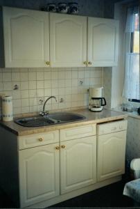 eine Küche mit weißen Schränken und einem Waschbecken in der Unterkunft Ferienwohnung Gotha in Gotha