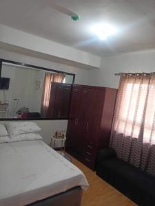 a bedroom with a bed and a mirror and a chair at Studio unit at Mesaverte Residence in Cagayan de Oro