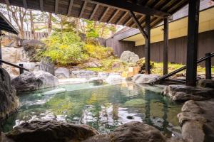 een zwembad met rotsen in een tuin bij Kusatsu Now Resort Hotel in Kusatsu