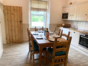 a kitchen with a wooden table with chairs around it at Netherraw in Newcastleton