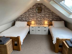 a attic bedroom with two beds and a stone wall at Netherraw in Newcastleton