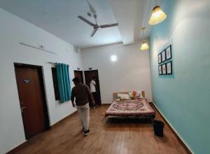 Un uomo che cammina in una stanza con un letto di Housefull Residency a Khandagiri