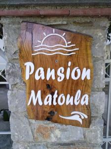 un panneau indiquant un restaurant dans un mur de pierre dans l'établissement Pansion Matoula, à Skiathos Chora