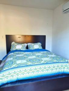 a bed with a blue comforter and two pillows at Casa Mar de Sueños Tamarindo in Tamarindo