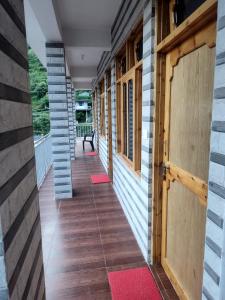 a hallway of a house with wooden doors and red rugs at Pranjal home stay in Polang