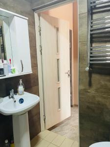 a bathroom with a sink and a toilet and a door at Natia rooms in Tbilisi City