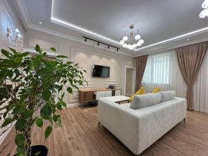 ein Wohnzimmer mit einem Sofa und einem TV in der Unterkunft Home Apartment Luxe in Schymkent