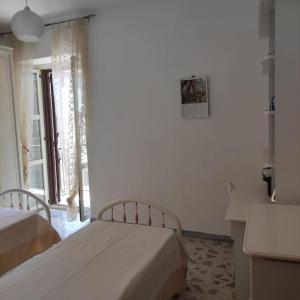a bedroom with two beds and a desk and a window at Delizioso appartamento al centro di Bosco in San Giovanni a Piro