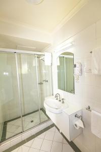 ein Bad mit einer Glasdusche und einem Waschbecken in der Unterkunft The Denman Hotel in Thredbo in Thredbo