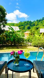 Peaceful Retreat Villa by Nai Thon beach في فوكيت تاون: طاولة عليها مشروب وبعض الزهور