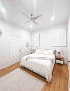 a white bedroom with a bed and a ceiling fan at Homestead on the Range - Sleeps 12 in The Range