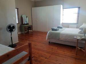 a bedroom with two beds and a wooden floor at Scheepers Rust Guest Farmhouse in Montagu