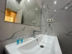ein Badezimmer mit einem weißen Waschbecken und einem Spiegel in der Unterkunft Home Apartment Luxe in Schymkent